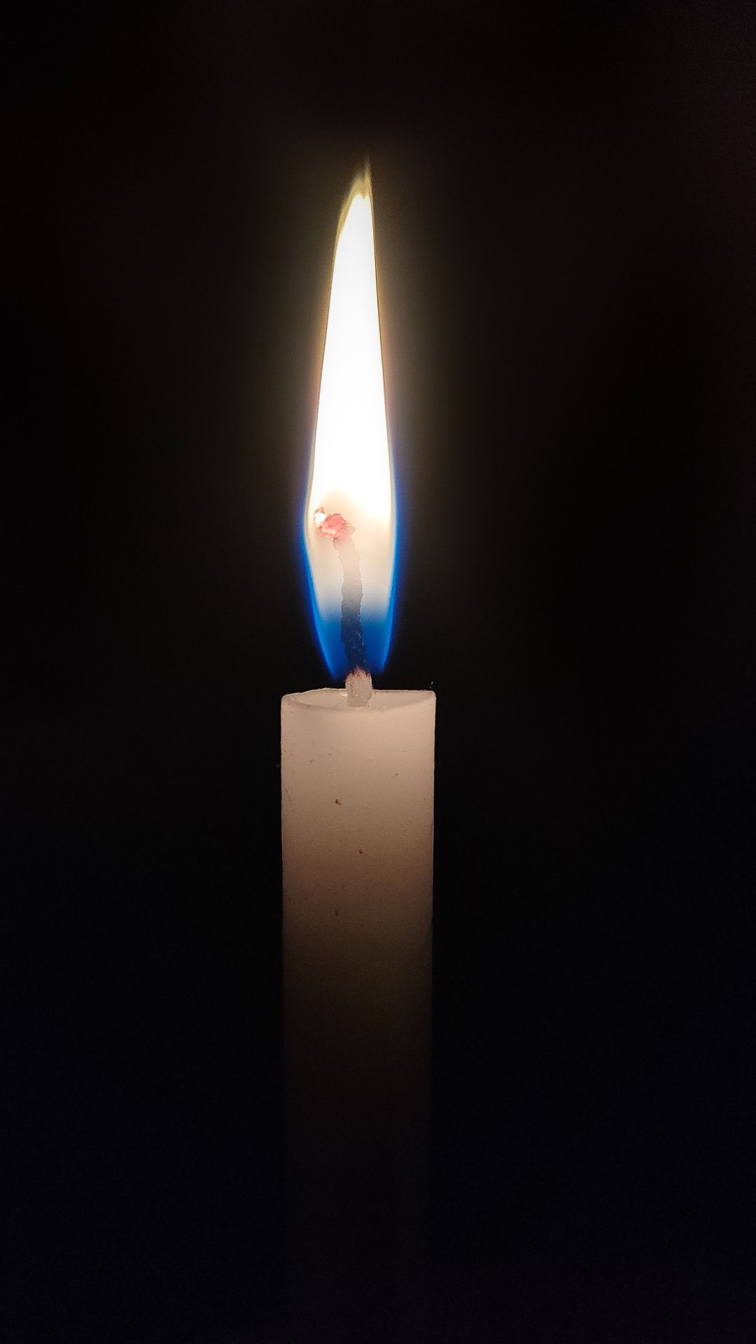 A single lit candle in the dark